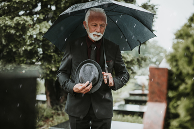image shows elderly man with umbrella at grave site for discussion on Pearce Law Group about dying without a will